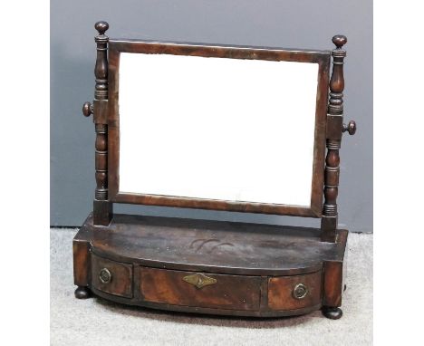 A late Georgian mahogany framed rectangular toilet mirror on turned uprights, the bow-front base fitted three drawers, on bun