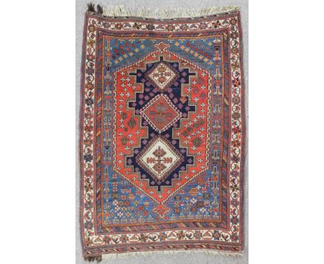 An antique North West Persian rug woven in colours with three hooked lozenge shaped medallions within angular central panel o