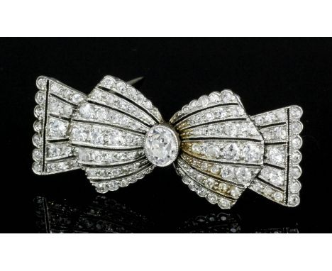 A 1920s silvery coloured metal mounted all diamond set bow pattern brooch, the central oval old cut stone approximately .50ct