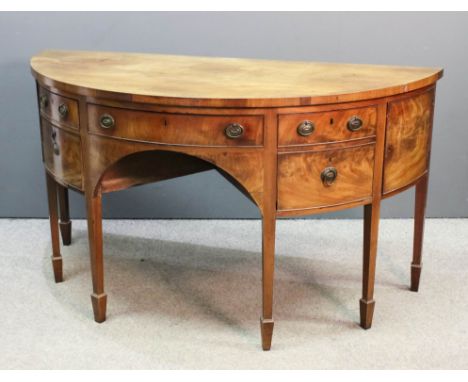 An Edwardian mahogany bow-front sideboard of Georgian design, fitted four drawers flanked by cupboards, on six square tapered