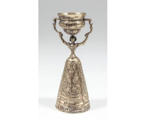 An early 20th Century Dutch silver gilt goblet modelled as a woman wearing a crinoline dress holding aloft a bowl, the whole 