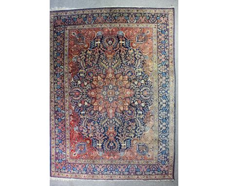 A Tabriz carpet woven in colours with a bold central medallion, hanging urn, deer, flowering trees and leaf ornament on a nav