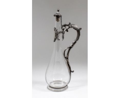 A late Victorian silver mounted liqueur decanter with plain glass bulbous body, the silver scroll handle and mount of sinuous