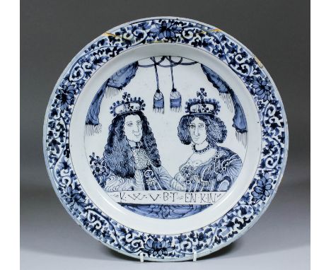 A late 17th Century Dutch Delft blue and white charger with a double portrait of William and Mary, the rim painted with styli