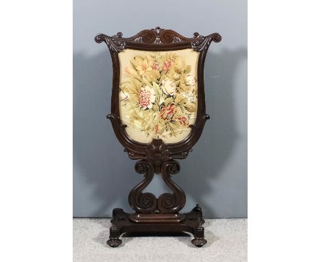An early Victorian rosewood framed shield shaped firescreen, inset with Berlinwork floral spray panel, with carved leaf and s