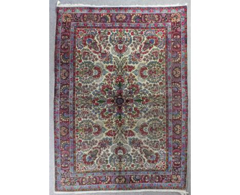 A Lavar Kirman carpet woven in colours with a bold floral central medallion and conforming floral and trailing leaf designs o