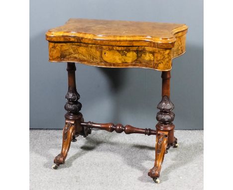 A Victorian figured walnut games table of serpentine outline, the quarter veneered folding top opening to reveal backgammon c