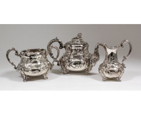 A Victorian silver three piece tea service, the squat baluster shaped bodies boldly embossed and chased with floral sprays an