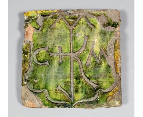 A late Medieval German relief stamped tile decorated with an heraldic frame and with the initials "CM" on a green glaze, 5.75