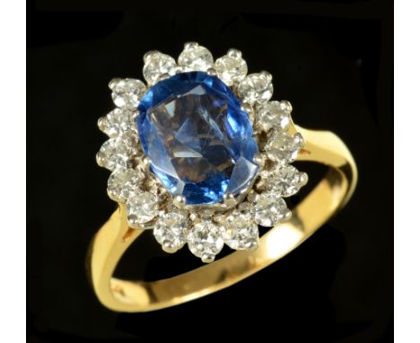 A Sapphire and Diamond Cluster Ring claw-set oval-cut sapphire within a frame of sixteen brilliant-cut diamonds in 18ct gold,