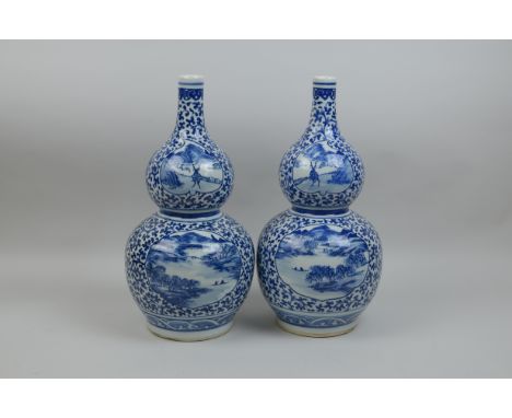 A pair of Chinese blue and white double gourd Vases painted reserve of figures on lake and deer in landscape, floral scroll a