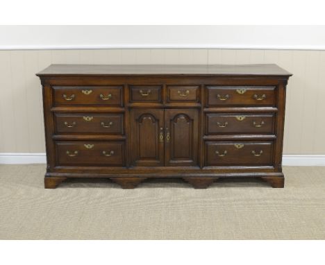 An 18th Century oak Dresser Base fitted eight drawers surrounding a pair of small arched panelled doors on bracket feet, 6ft 