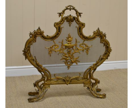 A 19th Century gilt metal Louis XV style Firescreen, the shaped and moulded frame with a central cartouche on a mesh web, rai