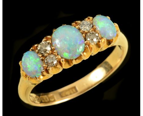 An Opal and Diamond Ring pavé-set three oval opal cabochons with pairs of old-cut diamonds between in 18ct gold, ring size N
