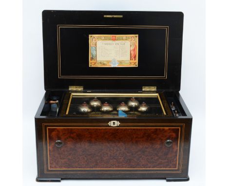 An early 20th Century walnut cased music box, the hinged cover opening to a brass key wound cylinder movement with steel comb