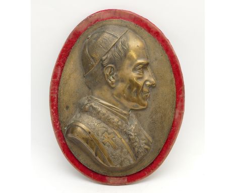 A gilt bronze plaque, depicting the Pope, possibly Pope Pius XII, on a red velvet oval mount, 49cm x 36.