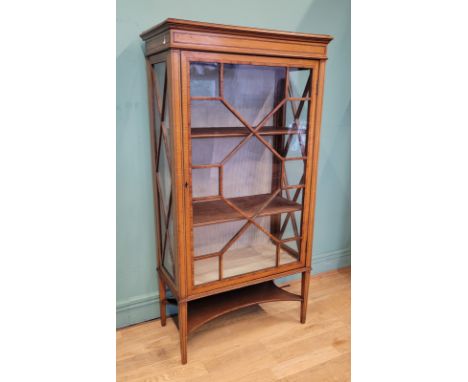 An Edwardian inlaid mahogany and satinwood display cabinet, having single glazed door opening to fitted shelves, with lower s