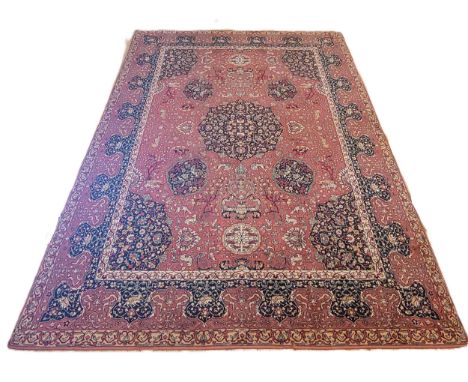 A large Persian Hamadan rug, pale red ground, the field decorated with floral urns and stylised foliate, curled leafy branche