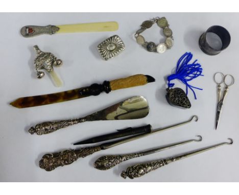 A collection of silver and white metal items to include a baby's rattle, pill box, page turners, coin bracelet, napkin ring, 