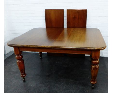 Mahogany extending dining table, the rectangular top with moulded edge, on bold baluster legs terminating on brass caps and c