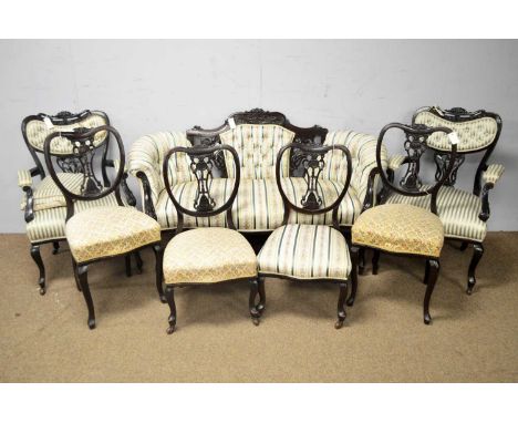 A late Victorian carved Salon Suite comprising a sofa, two armchairs and four side chairs.