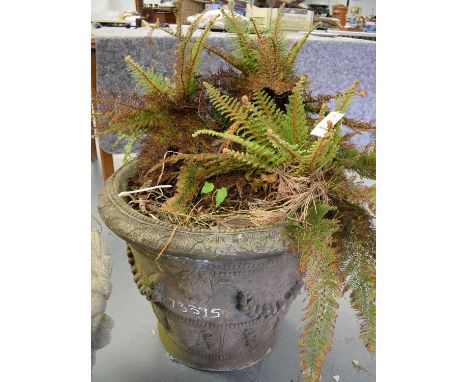 A stone composite garden planter, of tapering cylindrical form, decorated with borders of foliage, and faces interspersed by 