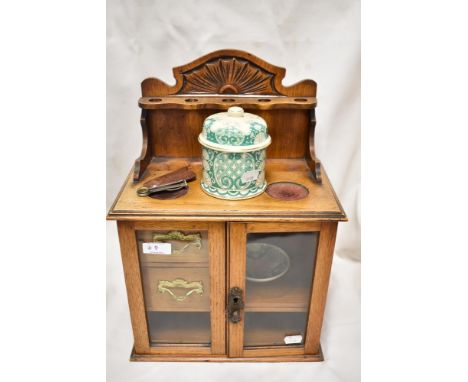 An early 20th century tobacco pipe smokers  compendium cabinet, having an Oak case with glazed doors and ceramic tobacco jar.