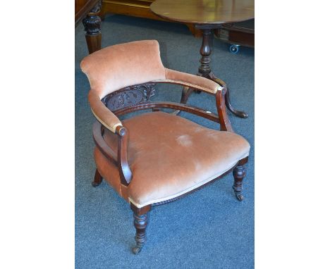A Victorian library chair, padded back and arm rail, carved splat, shaped stuffed overseat, turned fore legs, ceramic castors