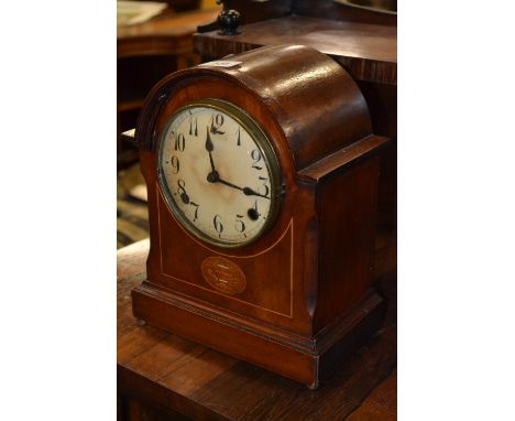 An Edwardian inlaid mahogany dome top mantel clock, inlaid with an oval panel within box wood stringing, brass bun feet.