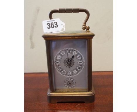 A brass carriage clock with an alarm feature with grey and gilt enamel dial      Clock appears to be working at time of inspe