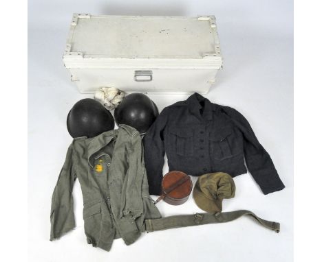 A vintage metal and wooden trunk, white painted, containing WWII jackets and two military helmets