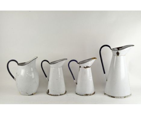 Four vintage white enamel jugs with blue handles, maximum height 38cm