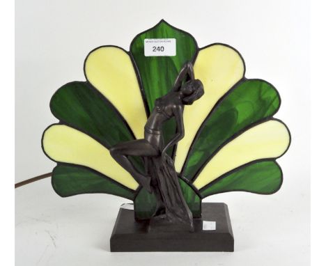 An Art Deco style cast metal table light, modelled as a reclining woman positioned in front of a green and yellow leaded glas