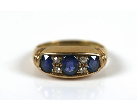 An 18ct gold sapphire and diamond ring, the largest oval cut sapphires approximately 3 by 4mm flanked by two smaller sapphire