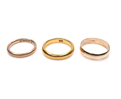 A group of three yellow gold wedding band rings, comprising one with marks obscured but tests as between 18 and 22ct, 3.7mm w