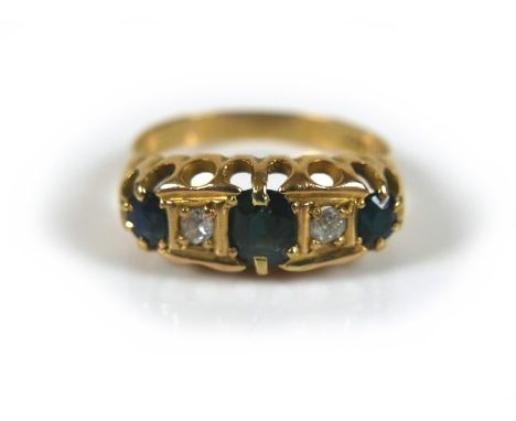 An 18ct gold sapphire and diamond ring, the largest oval cut sapphire, approximately 4 by 5mm, flanked by smaller sapphires e