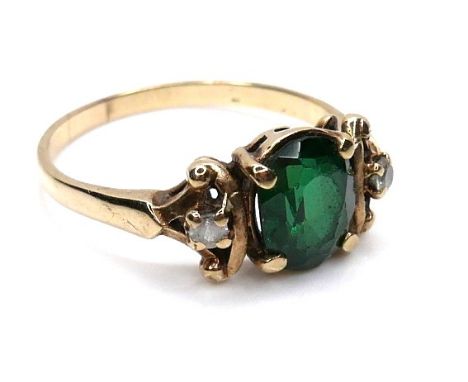 An Edwardian gold ring, the principle oval cut green paste stone, 8mm high, flanked by two small white stones, marks rubbed, 