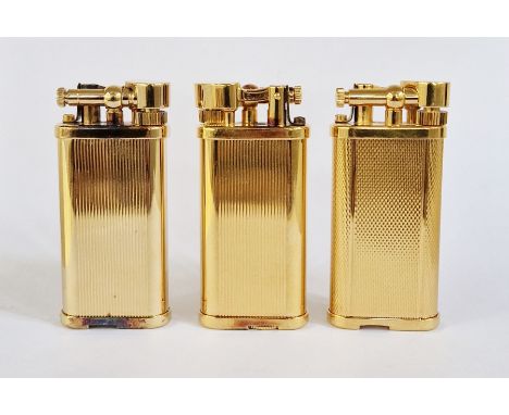 Three Dunhill gilt metal lighters with engine-turned decoration, no.120917, 45787 and 34677, each 6.5cm high (3)&nbsp;Conditi