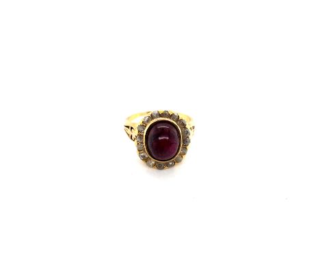 AN ANTIQUE GARNET AND DIAMOND CLUSTER RING. THE CENTRAL OVAL CABOCHON, SURROUNDED BY A CLUSTER OF SIXTEEN OLD ROSE CUT DIAMON
