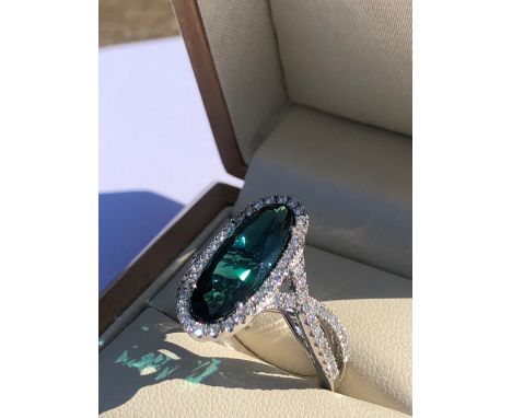AN 18ct HALLMARKED WHITE GOLD BLUE TOURMALINE AND DIAMOND RING. THE OVAL BLUE TOURMALINE MEASUREMENTS APPROX 18.2 X 7.7mm. FI