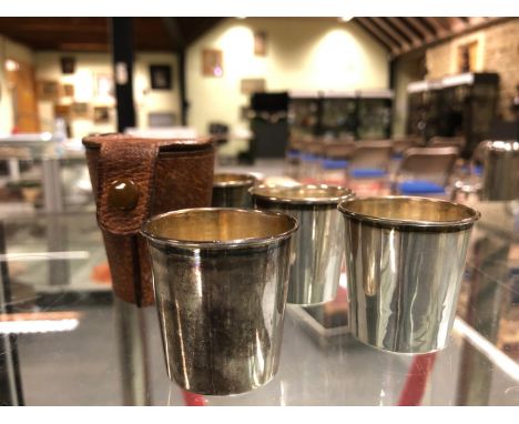 SET OF FOUR STERLING SILVER AND GILT WHISKY SHOT TOT GLASSES IN BROWN LEATHER BUTTON CASE.