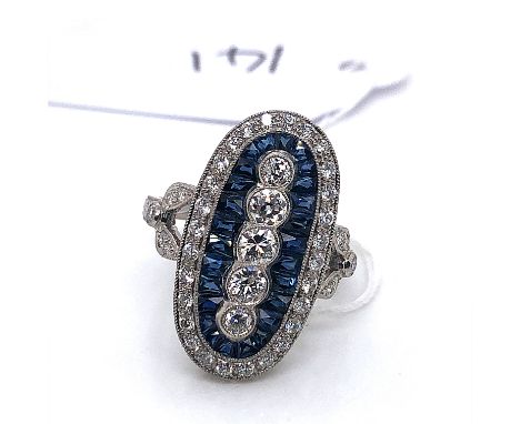 AN ART DECO STYLE PLATINUM, SAPPHIRE AND DIAMOND OVAL PANEL RING. THE FIVE VERTICAL CENTRAL OLD CUT DIAMONDS SURROUND BY A FI