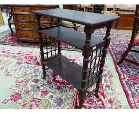 AN ARTS AND CRAFTS LIBERTYS STYLE OAK THREE SHELF STAND, WOOD GRILLES JOINING THE RING TURNED CYLINDRICAL LEGS BETWEEN THE SE