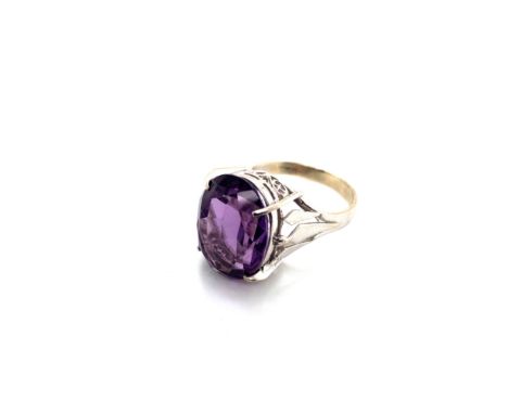 A OVAL AMETHYST COCKTAIL RING IN A RAISED PIERCED WORK SETTING, UNHALLMARKED ASSESSED AS 9ct WHITE GOLD. FINGER SIZE K 1/2. W