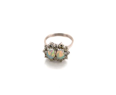 AN 18ct HALLMARKED WHITE GOLD OPAL AND DIAMOND DOUBLE CLUSTER RING, THE TWO OVAL OPALS IN CLAW SETTINGS SURROUNDED BY A CLUST