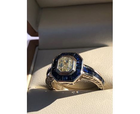 A SAPPHIRE AND DIAMOND ART DECO STYLE CHANNEL SET RING. THE CENTRAL DIAMOND IN A RUBOVER SETTING SURROUNDED BY A FRAME OF FAN