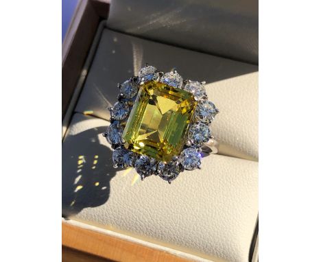 A YELLOW SAPPHIRE AND DIAMOND CLUSTER RING. THE CENTRAL YELLOW SAPPHIRE MEASUREMENTS APPROX 12.5 X  10mm, SURROUNDED BY A HAL