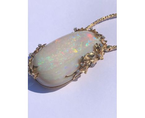 AN EXCEPTIONAL LARGE OPAL AND DIAMOND PENDANT, THE OVAL FORM OPAL MOUNTED IN A 14ct GOLD AND DIAMOND FRAME WITH FOLIATE DECOR