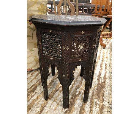 AN ISLAMIC OCTAGONAL TABLE, THE FOLIATE SCROLL CARVED TOP INSET WITH CENTRAL MOTHER OF PEARL AND EBONY STAR, REPEATED ON THE 