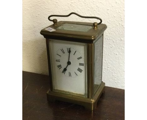 A brass carriage clock with white enamelled dial on bracket feet. By R&amp;C of Paris. Est. £30 - £50.